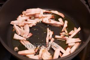 В большой сковороде разогреть 2-3 столовые ложки оливкового масла и обжарить бекон 5-7 минут до прозрачности.