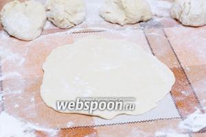 Поверхность, на которой будете раскатывать тесто, присыпать мукой. Разделить тесто на равные части — раскатать полученный комочек в лепёшку диаметром 25-30 см, толщиной 4-6 мм.