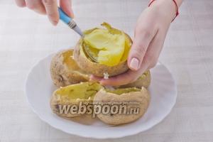 Запечённый картофель остудите. На каждой картофелине сделайте горизонтальный срез толщиной примерно 1,5 см. Аккуратно выньте мякоть и переложите в миску. Кожуру сохранить.