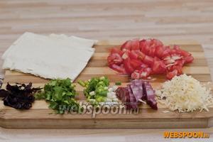Тесто делим на порционные куски, с помидора снимаем шкурку и режем кубиками, колбасу нарезаем продолговатыми ломтиками, петрушку, лук и базилик мелко режем, сыр трём на мелкой тёрке.