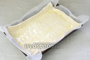 Форму для запекания застелить пергаментной бумагой, выложить тесто, проколоть вилкой в нескольких местах и смазать оливковым маслом. Поставьте форму с тестом в холодильник.