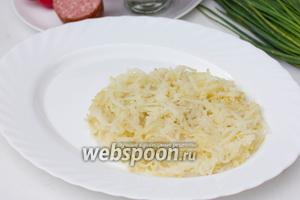 Натираем картофель на крупной тёрке и выкладываем на продолговатое плоское блюдо в виде овала по размеру предполагаемого «ананаса».