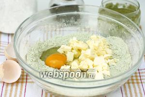 Холодное сливочное масло нарезаем мелкими кубиками, добавляем к сухим ингредиентам, туда же вбиваем яйцо и вымешиваем.
