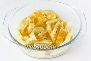 Перекладываем картофельные «палочки» в миску, посыпаем куркумой и вливаем оливковое масло. Тщательно перемешиваем.