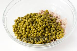 Открываем банку с консервированным горошком, жидкость сливаем, а горошек добавляем в салатник к мясу и луку.