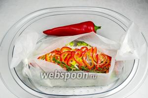Выложить рыбу с овощами в судок пароварки. Добавить один сладкий перец. Когда он запарится, использовать его для украшения блюда. Варить на пару в течение 20 минут.