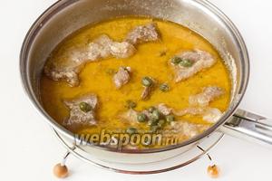 Перекладываем всё содержимое сковороды (мясо вместе с соусом) в сотейник или небольшую кастрюлю, доливаем кипячёную воду, накрываем крышкой, доводим на сильном огне до кипения, уменьшаем огонь до минимального и тушим свинину в кефире около 40 минут. Через 40 минут добавляем в сотейник каперсы и измельчённый чеснок. Перемешиваем, 3 минуты прогреваем и снимаем сотейник с плиты.