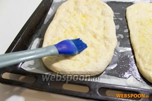 Противень для выпечки смажьте маслом, можете застелить пергаментной бумагой. Выложите на него лепёшки. Каждую лепёшку надо смазать сверху оливковым маслом, совсем чуть-чуть. Оставьте тесто, не накрывая, на 30 минут для подъёма. За это время всё масло впитается в тесто и за счёт него хлеб будет более ароматный и нежный.