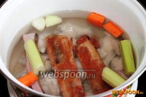 Наливаем в кастрюлю (объёмом 3-5 литров) чистую воду, помещаем курицу и разрезанные свиные копчёные рёбрышки, крупно нарезанные половинку луковицы, моркови и стебля сельдерея.
Доводим до кипения и варим на медленном огне 15 минут.