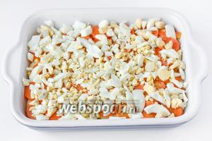 Отваренные яйца чистим и нарезаем средними кусочками. Выкладываем яичный слой поверх морковного.