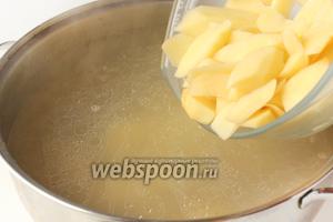 Выкладываем мясо обратно в бульон и всыпаем картофель. Когда бульон закипит вновь, убавляем огонь и продолжаем варить.