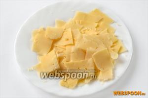 С помощью сырорезки или овощечистки нарезаем тонкие пластинки сыра, похожие на чипсы.