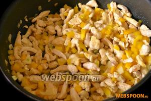 Добавляем перец и нарезанный тонкими пластинками чеснок к курице, продолжаем обжаривать вместе.