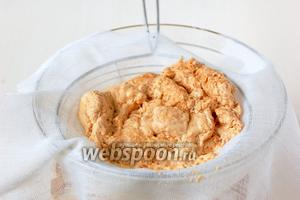 Отделить сыворотку от творожной массы из ряженки, вылив содержимое кастрюли в друшлаг с марлей.