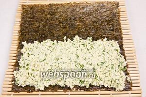 Нори положить на бамбуковый коврик и на каждый лист нори выложить примерно 3/4 стакана миндального сыра, полностью покрывая половину листа.