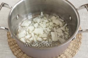 На дно кастрюли налить растительное масло, разогреть, добавить очищенный и мелко нарезанный репчатый лук. Слегка обжарить.