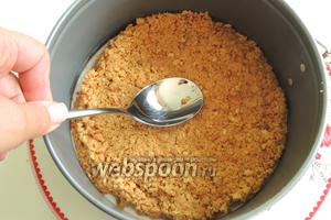 На блюдо выкладываем массу печенья размером с разъёмное кольцо. Хорошо прижимаем ложкой до образования плотного дна. Накроем и уберём в холодильник.