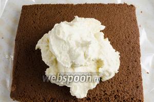 На пропитанный корж выложить третью часть крема. С помощью кулинарной лопатки распределить крем равномерно по всей поверхности коржа. Засыпать крем третьей частью шоколадной крошки.