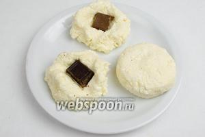 Отделить от теста кусок, сформировать лепёшку, вложить в середину начинку из кусочка шоколада, защипнуть. Сформировать сырник.