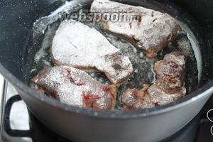 Разогреть масло в сковороде, а лучше в глубокой толстостенной кастрюле или казане. Обжарить печень с одной стороны до румяности в течение 3-5 минут.