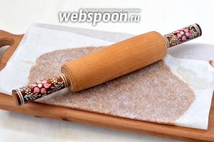Накрыть сверху пергаментной бумагой и пройтись сверху скалкой. Раскатать слой до толщины 1 мм.