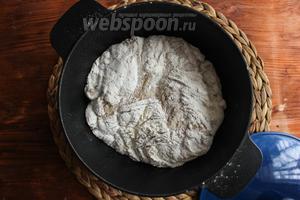 Поставьте в духовку чугунную кассероль с закрытой крышкой, чтобы она сильно нагрелась (примерно на 15-20 минут). После этого достаньте кассероль, снимите крышку и бережно переложите тесто в кастрюлю швом вниз, сделайте на хлебе надрез острым ножом. Постарайтесь захватить как можно меньше муки. Накройте хлеб крышкой и отправьте в духовку.