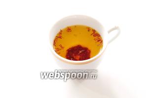 Щепотку шафрана аккуратно растолочь в фарфоровой кружке, залить тёплой водой (5 столовых ложек воды на щепотку шафрана) и накрыв блюдечком (чтобы не улетучился аромат), поставить рядом с плитой в тёплом месте настояться.