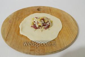 Кусочки теста скатываем в шарик, раскатываем в круглый пласт толщиной до 0,5 см. На середину выкладываем приблизительно по 1 столовой начинке и немножко разравниваем её по тесту.
