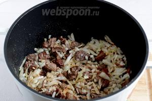 К мясу добавить мелко нарезанный лук и два зубчика измельчённого чеснока. Всыпать красный молотый перец, паприку и имбирь. Раньше имбирь не добавлялся, но сейчас ему всё больше отдают предпочтение. Жарить всё вместе до мягкости лука, минут 7.