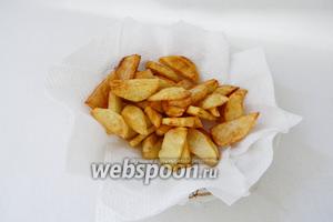 Остальной картофель обжариваем во фритюре до золотистого цвета и выкладываем в тарелку с салфетками, чтобы впитать лишний жир.