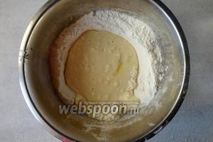 Затем вливаем кислое молоко тонкой струйкой, при этом замешиваем тесто руками круговыми движениями.