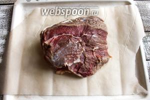 Возьмите плоский противень и выстелите его пергаментной бумагой. Мясо промойте под струей холодной воды, тщательно обсушите бумажным полотенцем и срежьте плёнку. Ещё раз промокните бумажным полотенцем и положите на противень.