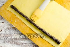Кисточкой промазать тесто яичной намазкой за валиком маковой начинки.