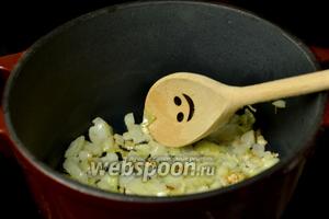 Разогреваем в чугунной кастрюле подсолнечное масло (раньше выжаривали до шкварок кусочки свежего сала, но я это делать не стала). Кладем лук и чеснок, помешиваем, пока лук не станет мягким и прозрачным.
