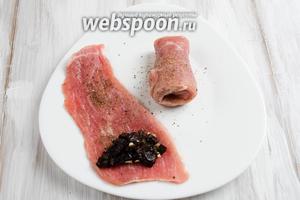 На край куска мяса выложить немного начинки. Скрутить рулетом. Закрепить (обвязать вокруг) с помощью кулинарной или обычной нити.