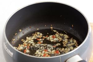 В разогретой смеси кунжутного и подсолнечного масла быстро обжарить чеснок и чили до появления запаха.