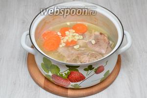 Кладём нарезанный чеснок и морковь, солим по вкусу. Ставим кастрюлю обратно на огонь ещё на полчаса.