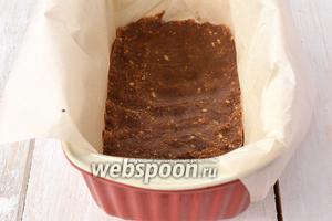 Длинную и глубокую форму для кексов выложить кулинарной бумагой и на дно выложить крошку из печенья. Хорошо утрамбовать.
