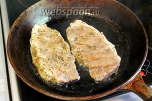 Разогреть в сковороде масло, положить мясо, убрав с него лук и чеснок, которые оставить в маринаде. Огонь печи убавить до среднего, жарить с одной стороны 5 минут.