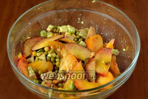 Складываем в общую посуду кукурузу, зелёный горошек, авокадо, персик, помидор, вливаем соус, двумя осторожными движениями снизу вверх смешиваем.