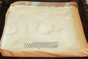 Подходящей формы у меня нет, поэтому я поступаю следующим образом. Беру лист пергамента (примерно 40 на 40) и делаю бортики (около 4 см), закрепляя их с помощью степлера. Помещаем пергамент на противень. Выкладываем в импровизированную форму тесто, разравниваем его. Выпекаем ровно 15 минут при 180ºC.