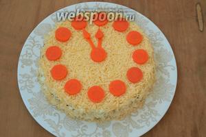 Из варёной моркови вырезать кружочки для циферблата и стрелки часов. Разложить кружочки по кругу, сделать стрелки.