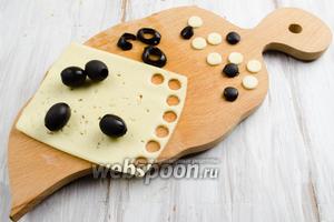 Подготовим вырубку для круга, размером меньше нашего квадрата 2х2 см. С помощью вырубки нарезать из пластины сыра несколько белых «шашек». А из маслин — несколько чёрных «шашек».