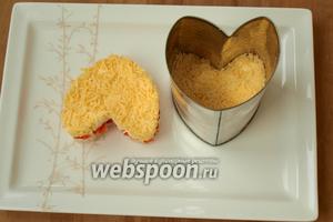 С помощью формочки собрать 2 сердечка: женское и мужское. Женское сделать перевёрнутым вниз, слои будут в таком порядке: кальмары-перец-желтки-сыр, между слоями обязательно промазывать майонезом. Утрамбовать салат и снять форму. Также сделать мужское сердце, только слои будут немного другие: кальмары-перец-белки-сыр. Обязательно промазать майонезом.