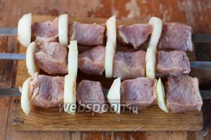 Нанизываем на шампура, чередуя ломтики мяса с колечками лука. Параллельно разогревается мангал с дровами.