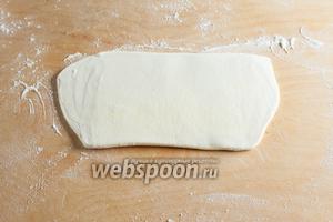 На обсыпанной мукой рабочей поверхности тесто раскатывается в вытянутый прямоугольник толщиной 1 см.