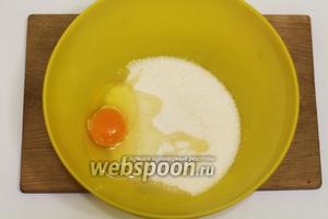 В подходящей глубокой посуде соединяем куриное яйцо и сахар. Перемешиваем деревянной ложкой до однородного состояния.