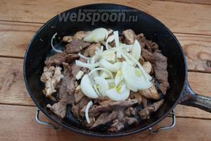 К обжаренному мясу добавьте репчатый лук. Потом добавляем шампиньоны. Жарим всё вместе до готовности.
