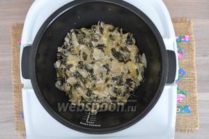 В чашу мультиварки налить немного масла и выложить 1/2 картофеля, равномерно распределяя по чаше. На картофель выложить ровным слоем весь папоротник.