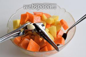 Этим временем подготовим картофель и тыкву. Почистим и нарежем на кубики. Приправим оливковым маслом и солью. Выжмем через пресс зубок чеснока и всё вместе перемешаем.